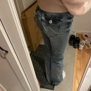 Blå bootcut jeans med fickdetaljer - Säljer Lowwaist bootcut jeans ifrån Nelly andvända 2 gånger med fina detaljer på fickorna 