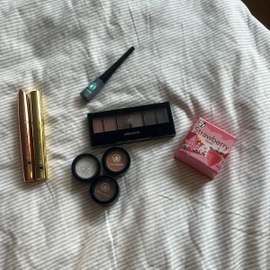 Sminkpaket med mascara, eyeliner & ögonskuggor - Säljer ett sminkpaket med två mascaror (volym och längd) i metallic guld och koppar, silvrig flytande eyeliner, en ögonskuggspalett med sex nyanser i bruna och grå toner, tre singelögonskuggor (vit, brun, taupe) samt ett rouge från W7 i söt rosa förpackning med jordgubbsdesign med en jätte fin färg🍓 Allt är oanvänt🙌🏻🫶🏻
