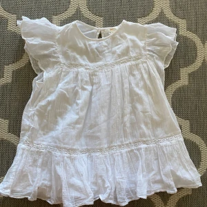 Vit volangtopp från Gina Tricot - En topp från Gina Tricot. Kort, skön och perfekt sommar topp. Använd och tvättad. Finns ej på Ginas hemsida längre. 