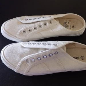Vita sneakers strl 37 - Vita sneakers i storlek 37. Skorna är vita med diskret glitter och har en klassisk design.  De är bara prövade. Perfekta luftiga sommarskor.