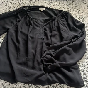 Svart blus från & Other Stories - Säljer en svart blus från & Other Stories i storlek M. Blusen har långärmade ärmar, snygga spetsdetaljer vid halsringningen och ärmarna samt en lös passform. Materialet känns mjukt och har ett fint fall, perfekt för en stilren look.