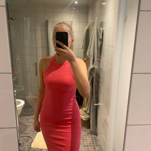 Rosa ribbad tight klänning - Säljer en rosa ribbad klänning med tight passform och ärmlös design. Klänningen har rund halsringning och sportig ryggskärning, perfekt för dig som gillar en enkel men snygg stil. Materialet är stretchigt och följsamt.