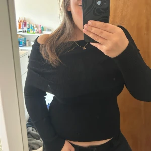 Svart offshoulder stickad tröja Soya Concept - Svart stickad tröja från Soya Concept med offshoulder-design. Tröjan är ribbad och har lång ärm, sitter snyggt figurnära och är perfekt för dig som gillar en stilren look med lite edge.