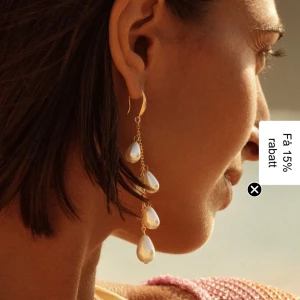 Långa örhängen med pärldroppar - Snygga långa örhängen i guldton med kedja och flera vita droppformade pärlor. De har en elegant och modern look som verkligen sticker ut. Perfekta för dig som vill ha något extra till din stil.