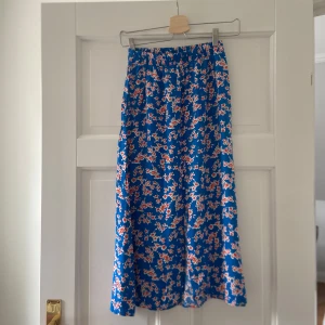 Superfin blommig blå långkjol från märket Pieces i XS - Jättesnygg blommig kjol som är i väldigt bra skick, den är super skön/sval och är perfekt nu till våren&sommaren🌸 Väldigt fin till speciella tillställningar som tex midsommar eller bara i vardagen🤍Den är enkel att styla, väldigt fint mönster, fin slits och knappar lägst kjolen⭐️den är stretching, har bra passform, bra material/kvalitet och är dessutom unik och så somrig med de fina blommorna på👌🏻den är en lite kortare långkjol kan man säga(medium lång)👍🏻 Skriv om funderingar&priset kan diskuteras😊