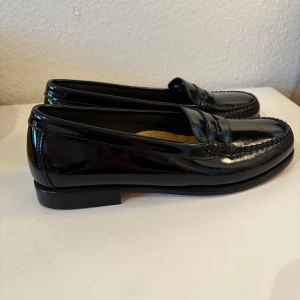 Svarta Weejuns loafers i skinn - Klassiska svarta loafers från Weejuns i blankt skinn. Penny loafer-modell med rund tå och låg klack. Handgjorda i äkta läder med snygg detaljsöm runt tåpartiet. Perfekta för en stilren och tidlös look. Priset kan diskuteras! Bara använda enstaka gång.  !!Finns på fler sidor!!
