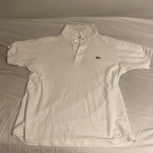 Vit pikétröja från Lacoste - Klassisk vit pikétröja från Lacoste. Storlek 3