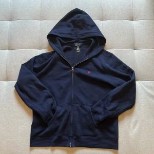 Mörkblå hoodie från Polo Ralph Lauren - Mörkblå hoodie från Polo Ralph Lauren med dragkedja och huva. Priset är ej hugget i sten vid snabb affär! Tveka inte på att skriva vid funderingar/frågor🤝