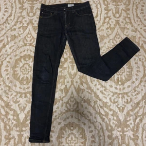 Mörkblå skinny jeans Tiger of Sweden - Snygga mörkblå skinny jeans från Tiger of Sweden med klassisk femficksdesign och kontrastsömmar. Jeansen har en smal passform och är tillverkade i ett stretchigt denimtyg som sitter tajt längs benen. Perfekta för en stilren och modern look.