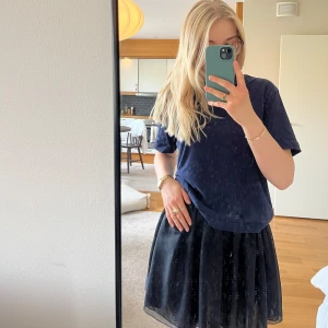 Svart kortkjol i tyll - Säljer en svart kortkjol i tyll med lätt volym och flowig känsla. Kjolen har en klassisk, enkel design och är perfekt att styla med en t-shirt eller stickad tröja. Resår i midjan för skön passform.