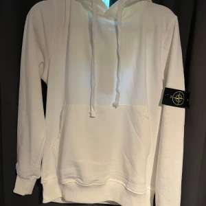 Vit stone island hoodie - Säljer min vita stone island hoodie som jag aldirg använt. Har ettiketen kvar och men inte kvittot för fick den i present. Dm för mer bilder