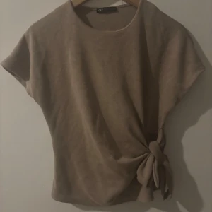 Beige stickad topp med knyt från Zara - Populär och eftertraktad knyt rop ifrån zara i storlek S men passar även xs , säljer då den aldrig har kommit till användning och därav inga defekter ☺️ vis bättre eller klarare bilder är det bara att skriva