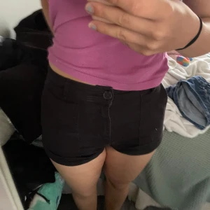 Svarta tighta shorts med hög midja - Säljer ett par svarta shorts med hög midja och tight passform.  knapp och dragkedja framtill samt fickor bak. Perfekta för varma dagar när du vill ha en clean och enkel look.
