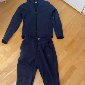Mörkblå Nike tech fleece med dragkedja - Säljer nu min mörkblåa Nike tech fleece dress  då jag inte använder den längre. Väldigt bekväm och ha på sig hemma men också väldigt skön och ha ute. Vid mer frågor hör av er!