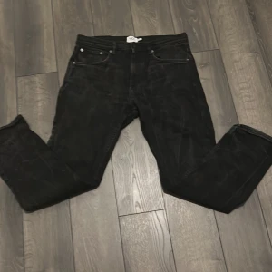 Svarta raka jeansbyxor - Straight Jeans. Svarta jeansbyxor med klassisk femficksdesign och raka ben. Byxorna har bälteshällor och silverfärgade nitar vid fickorna. Perfekta för dig som gillar en enkel och stilren look. Passar till det mesta och är lätta att matcha. 