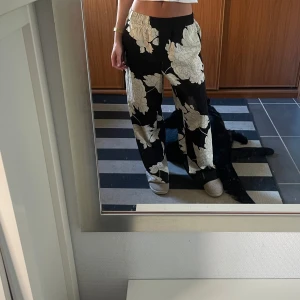 Svarta vida byxor med blommigt mönster - Flowy och svalt material! Använda endast ett par gånger. Är 171 cm. 