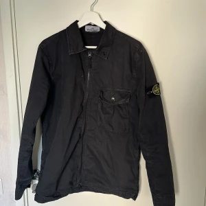 Stone Island Overshirt svart  - Svart overshirt från Stone Island, bröstficka med knapp och en clean, stilren look. Passar hur bra som helst på sommaren höst och våren, bär den själv alltid med Tröja under. 