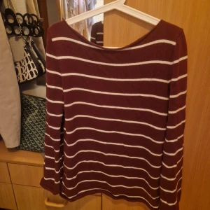 Randig vinröd stickad tröja NA-KDx Lojsan Wallin - Säljer en vinröd stickad tröja från NA-KD i storlek S. Tröjan har vita horisontella ränder och en rundad halsringning. Långärmad och i mjukt stickat material, perfekt för att ge din outfit en chill vibe. NAKDxLojsan Wallin