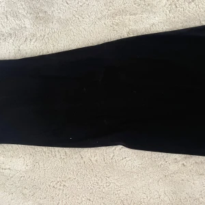 Svart ribbad kjol Stories XS - Svarta ribbad kjol från Stories i storlek XS (32-34). Den är stretchig och sitter tight, perfekt för en chill och snygg look. Materialet är mjukt och följsamt, med en låg midja som ger en bekväm passform. Kan även användas som en tube klänning.