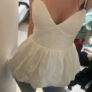 Vit volangig linnetopp med v-ringning - Supersöt vit topp köpt på missary. v-ringad omlott framtill och bred volangig nederdel. Smala axelband och smockad rygg för skön passform. Perfekt till jeans eller kjol för en fräsch look. Materialet känns lätt och luftigt. Aldrig använd❤️