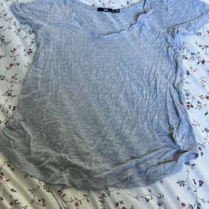 Ljusgrå t-shirt från Sportsgirl XS - En enkel ljusgrå t-shirt från Sportsgirl i storlek XS. T-shirten har korta ärmar, rundad v-ringad hals och är gjord i mjuk bomull. Passformen är normal och tyget är tunt och skönt mot huden. Perfekt för chill dagar och enkel att matcha med jeans eller shorts.
