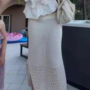 Beige stickad långkjol med slits - Superfin beige stickad långkjol med ribbad midja och snygg slits på sidan. Kjolen har ett coolt hålmönster nedtill och är gjord i mjukt stickat material som ger en chill och trendig vibe. Perfekt att styla med sneakers eller sandaler för en fräsch look.