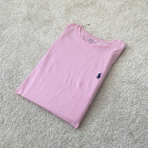 Rosa t-shirt från Polo Ralph Lauren - Ralph lauren t-shirt | Skick – 8/10 | Size – S | Hör av dig vid minsta fråga eller fundering!! Blå fläck på tröjan se bild! Och liten fläck vid logan!