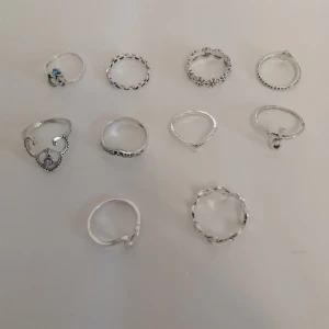 10 st silverfärgade ringar  - 10 st  silvriga ringar i olika former och mönster. Perfekt för dig som gillar att mixa och matcha flera ringar på samma hand. Materialet är zinc alloy. (296)