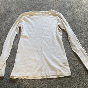 Vit långärmad tröja i bomull - Enkel och stilren vit långärmad tröja i ekologisk bomull. Perfekt basplagg med rund hals och normal passform, passar dig som gillar en clean och klassisk look. Skön och mjuk mot huden.