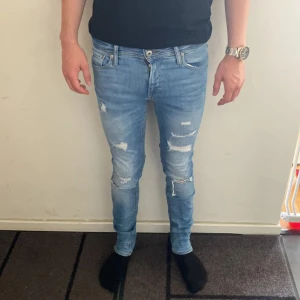 Jeans jack and jones  - Säljer ett par ljusblå skinny jeans från Skinny/Liam i storlek 28/32. Jeansen har slitna detaljer och hål på benen för en cool, trendig look. Klassisk femficksmodell med låg midja och stretchigt denimtyg som sitter tight längs benen. Modellen är 178 cm och väger 62 kg. Det är bara att höra av sig vid frågor och funderingar 😁