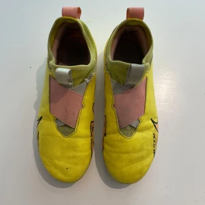 Nike Zoom Mercurial Vapor 15 Academy FG/MG – Strl 36,5 - Snabba och lätta fotbollsskor – perfekta för unga spelare! Nike Zoom Mercurial Vapor 15 Academy FG/MG i storlek 36,5. Färg: Yellow Strike/Sunset Glow/Black. Bekväma med Zoom Air-dämpning och utmärkt grepp på både natur- och konstgräs. Nypris ca 950 kr (2022). Skicket: gott och funktionsdugligt, med normalt slitage på dobbar och ovandel.  Finns i Spånga 
