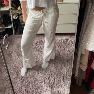Vita linnebyxor med snörning från Roxy - Snygga vita linnebyxor med avslappnad passform och dragsko i midjan från Roxy. Byxorna har raka ben, två fickor framtill och är perfekta för en chill och fräsch look. Lätta och luftiga, perfekta för varmare dagar. Köpt för 600kr, skriv för fler bilder eller frågor 
