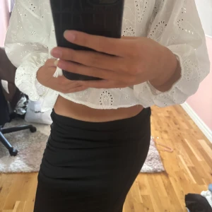 Svart kjol med slits - Säljer en svart lång-midi kjol med tight passform och liten slits på sidan. Kjolen har en ”scrunch” detalj på sidan, perfekt om du gillar minimalistisk stil. Materialet känns mjukt och stretchigt, vilket gör den bekväm att bära hela dagen. Använd 2 ggr