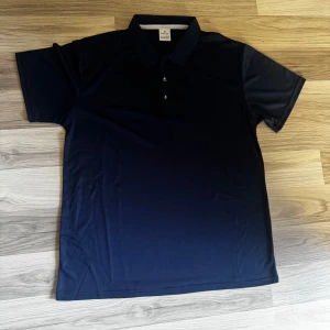 Mörkblå pikétröja i polyester - Snygg mörkblå pikétröja i storlek S med klassisk krage och tre knappar framtill. Tillverkad i 100% polyester som ger en lätt och skön känsla. Perfekt för dig som gillar stilrena och sportiga plagg. Passar dig som vill ha en enkel och clean look.