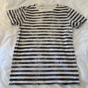 Svartvit randig t-shirt  - Snygg svartvit t-shirt  med horisontella ränder i en lite sliten look. Klassisk rund hals och korta ärmar. Materialet är mjuk bomull som känns skönt mot huden. Perfekt för dig som gillar en enkel men cool stil.