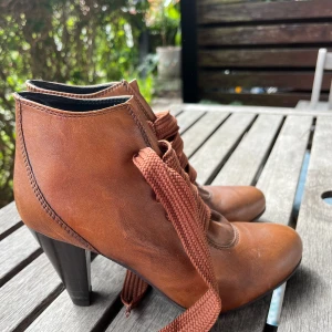 Bruna snörade stövletter Ilse Jacobsen - Snygga bruna stövletter från Ilse Jacobsen med breda snören och klack. Skorna är i skinn och har en rund tå samt platt sula framtill. Perfekta för dig som gillar klassisk stil med en twist. Det står 36 men storleken är liten. 