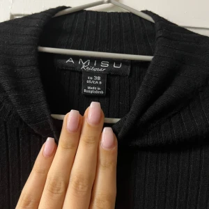 Svart ribbad klänning från Amisu Strl 38 men sitter som 36 - Svart ribbad klänning från Amisu i storlek 38 men sitter som en strl 36. Tröjan har lång ärm och en krage som ger en clean och stilren look. Materialet är mjukt och stretchigt, perfekt för hösten och vintern.