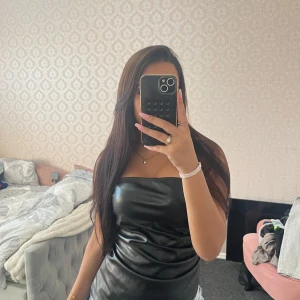 Svart tubtopp i skinnimitation - Säljer en svart axelbandslös tubtopp i skinnimitation. Toppen har en glansig finish och sitter tight över bröstet. Perfekt för dig som vill ha en edgy och trendig look. Enkel att matcha med både jeans och kjol.🩷🩷