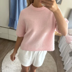 Ljusrosa stickad tröja från Gina tricot  - Superfin ljusrosa stickad tröja från Gina tricot med korta ärmar och rund hals. Tröjan har en loose passform och är gjord i mjukt material som känns skönt mot huden. Perfekt att styla med jeans eller kjol för en chill look.