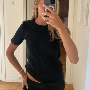 Svart T-shirt med volanger. - Supersöt T-shirt som är perfekt när man vill hålla det cleant men ändå lite detaljer. Strl S