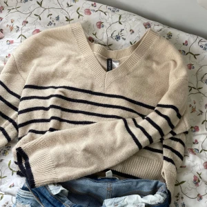 Beige stickad randig tröja H&M  - Säljer en beige stickad tröja från H&M Divided i storlek S. Tröjan har svarta horisontella ränder, v-ringad hals och långa ärmar. Jätte gullig att ha off-shoulder❣️ Använd fåtal ggr och jättefin inför hösten💕 tryck gärna på köp nu, priset går att diskutera och kontakta för mer frågor🤭❤️