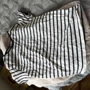 Randig vit t-shirt från Monki - Vit t-shirt från Monki med svarta horisontella ränder och rund hals. Klassisk kortärmad modell i mjuk bomull, perfekt för chill dagar. Snygg och enkel att matcha med jeans eller shorts. Passformen är normal och tyget är lätt och skönt.