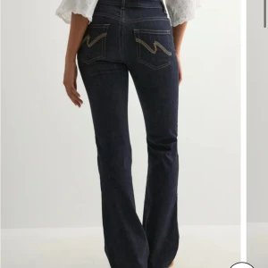 Bootcut jeans midwaist från Nelly - Mörkblå bootcut jeans från Nelly i modellen Mid Waist Perfect Bootcut. Snygg kontrastsöm och cool broderad bakficka. Jeansen är tillverkade i jeansmaterial med skön passform. Dem har aldrig blivit använda med lapppen kvar. 