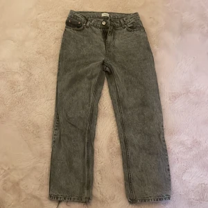 Grå jeans från Grunt - Snygga grå jeans från Grunt med raka ben och klassisk femficksmodell. Jeansen har normal midja, bälteshällor och metallknapp framtill. Perfekta för en avslappnad och trendig look.