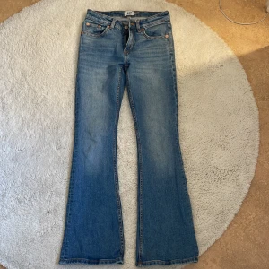 Blå bootcut jeans från 157 - Snygga blå jeans från 157 med klassisk femficksdesign och bootcut-ben. Jeansen har normal midja och är tillverkade i ett mjukt denimtyg med lätt tvättad look. Perfekta för dig som gillar en retro vibe och vill ha ett par jeans som sticker ut.