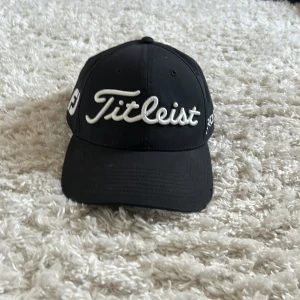 Svart Titleist keps Pro V1 - Säljer min Titleist keps, Kepsen är minimalt använd och är utan fläckar och är inte heller solblekt. Skriv vid eventuella frågor/funderingar