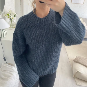 Mörkblå stickad tröja från 157 - Säljer en chunky mörkgrå stickad tröja från 157 med bred ribbad struktur och hög rund hals. Tröjan har långärmade, lite loose passform och är perfekt för kyliga dagar. Storlek 160 men är oversized och passar någon som bär xs.