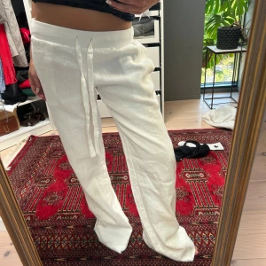 Vita linnebyxor med snörning  - Snygga och luftiga vita linnebyxor från Alobha the labelx, helt oanvända. Byxorna har raka ben och avslappnad passform, perfekta för en chill och stilren look. Materialet är svalt linne som passar grymt bra till varmare dagar.