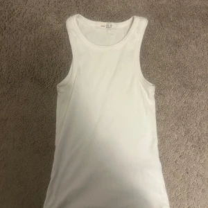 Vit ribbad linnetopp från OYSHO XS - Säljer en klassisk vit ribbad linnetopp från OYSHO i storlek XS. Toppen är ärmlös med rund halsringning och har en tight passform. Perfekt att styla med jeans eller shorts för en enkel och fräsch look.