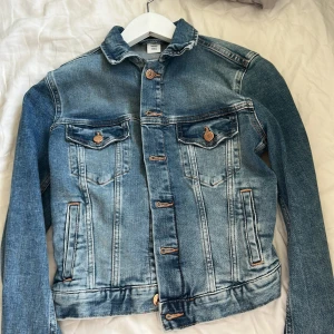 Klassisk blå jeansjacka - Säljer en klassisk blå jeansjacka med snygga kopparfärgade knappar och två fickor.Jackan har en tidlös passform, långa ärmar och har en lite stentvättad färg . Perfekt att till hösten💕